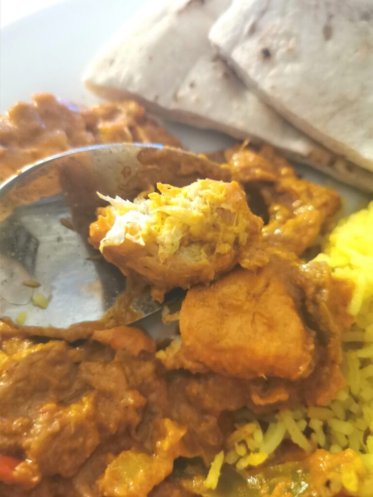 close up of piece of shicken tikka masala on a spoon