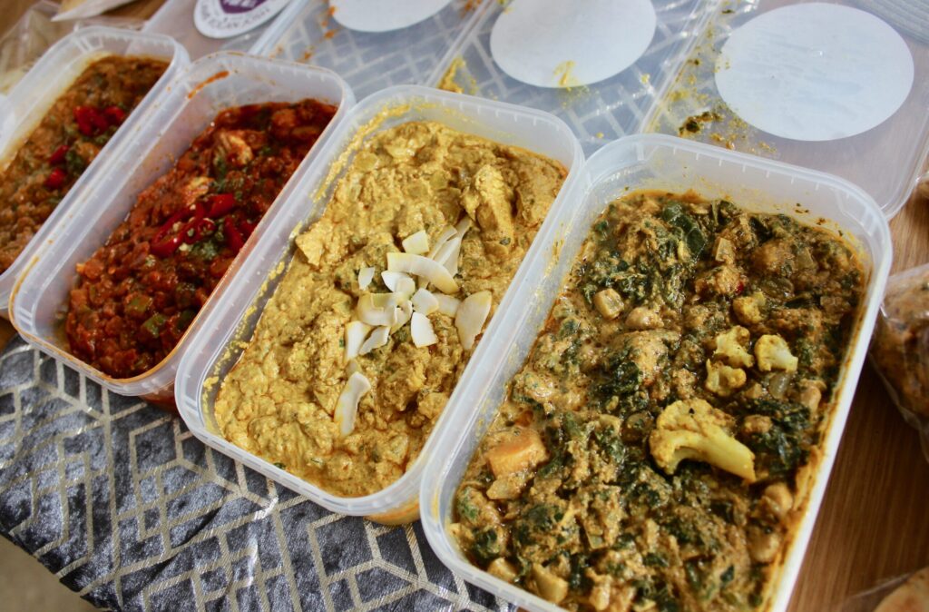 A close up of 4 curries from meals for all with their lids off